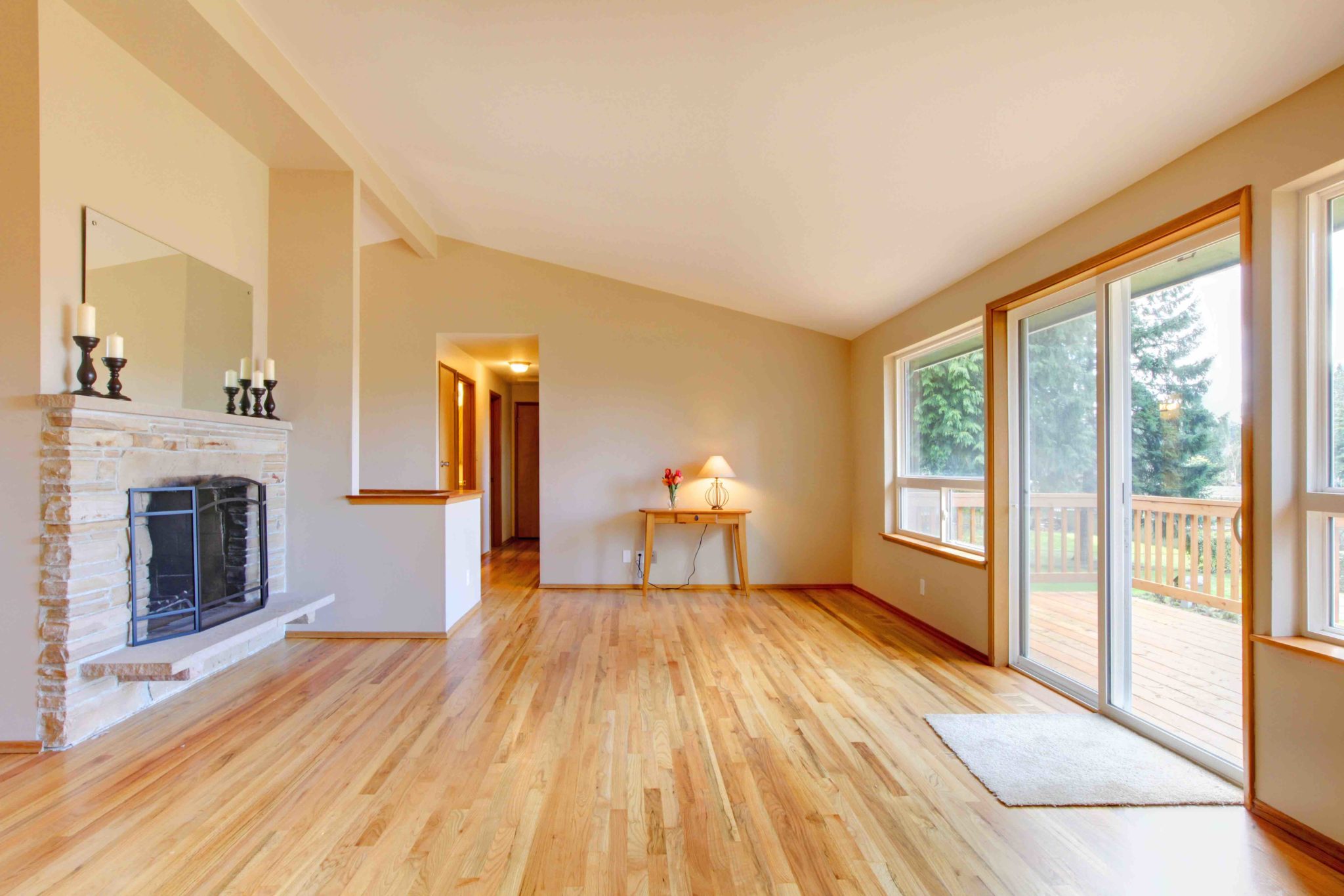 Empty living room with a fireplace, hardwood floor and sliding glass door exit to the deck